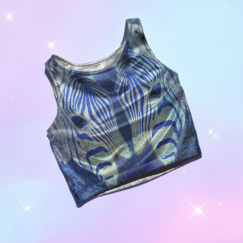 A women's sleeveless, high-neck crop top made from a performance spandex knit fabric. The top is designed with a body-hugging fit and features a striking, symmetrical digital graphic of a zebra's face. The intricate print uses shades of electric blue, cobalt, and navy, contrasted with a shimmering silver glitter effect that outlines the zebra's stripes and features. The psychedelic, futuristic design covers the entire front of the shirt.